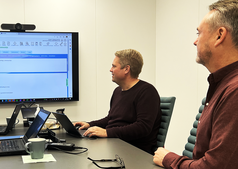 Roy Ulvang og Asbjørn Solberg-Eriksen sitter ved et bord, foran en stor skjerm der portalen Mercell er synlig.